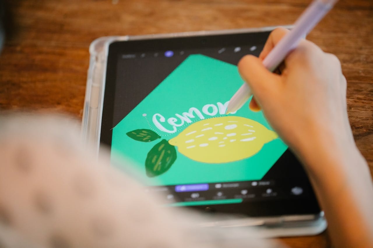 a person colors in an image of a lemon on a tablet